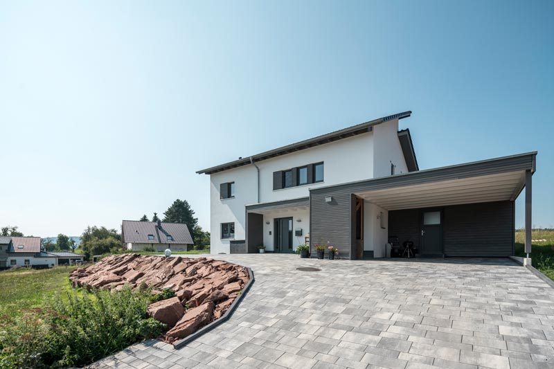 Holzhaus mit Carport und weißer Fassade